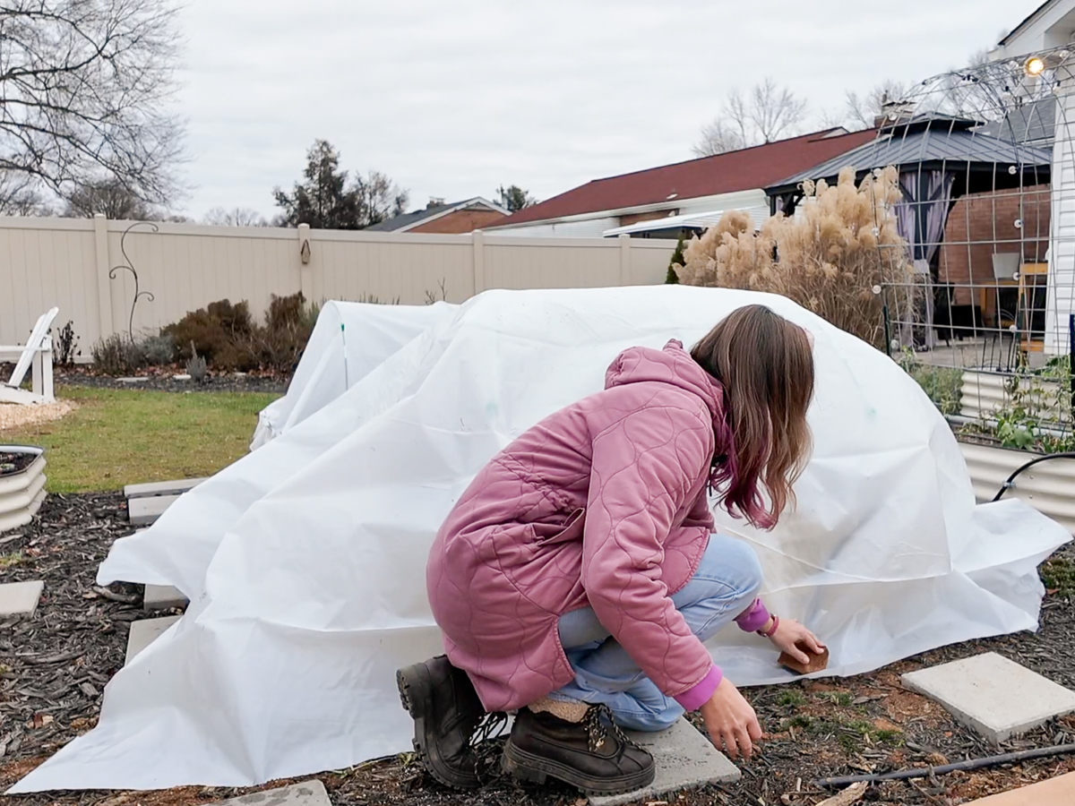 adding plastic sheeting to a hoop house